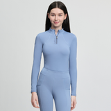 Woman wearing a light blue horse riding outfit on a grey background