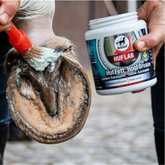 Person applying HUF LAB hoof grease to a horse's hoof with a brush.
