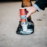Hand applying product to horse hoof, product up side down
