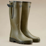 Pair of green rubber boots on a beige background
