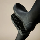 Black rubber boot with a thick sole on a beige background