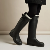 Black rubber boots worn with a neutral background