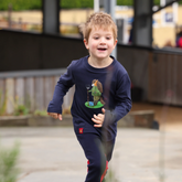 Young boy wearing a long sleeved navy blue top running in an outdoor setting