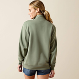 Woman wearing a green sweatshirt and denim shorts on a beige background