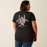 Person wearing a black t-shirt with a floral design on the back against a beige background