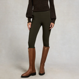 Person wearing green leggings and brown knee-high boots on a plain background