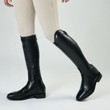 Black knee-high boots worn with beige riding leggings on a white background