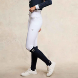 Person wearing white riding breeches with black socks on a beige background