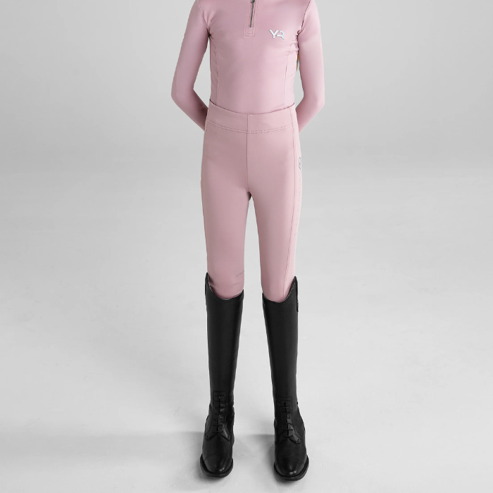Person wear pink riding leggings and black boots on a grey background