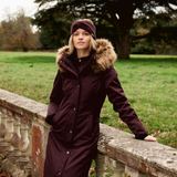 Woman wearing a dark purple coat with fur hood in a park setting