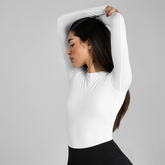 Woman wearing a white long-sleeve top against a grey background