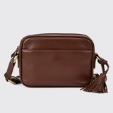Brown leather crossbody bag with tassel on a light grey background