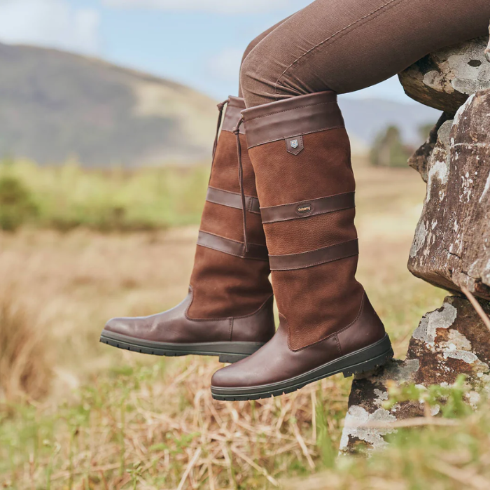 Person wearing a pair of brown leather country boots in an outdoor setting