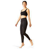 Woman wearing black athletic leggings and sports bra on a white background