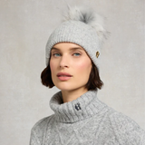 Woman wears a grey beanie hat and grey sweater on a grey background