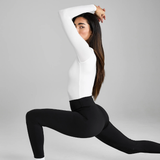 Person wearing a white long-sleeve shirt and black leggings on a grey background