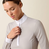 Woman wearing a light grey top with a white collar over a beige background