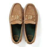 Pair of tan loafers with gold logo on a white background