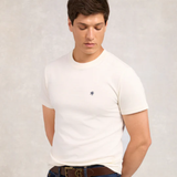 Man wearing a white t-shirt with a small logo on a plain background