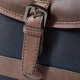 Close-up of a brown leather strap on a navy blue bag with stitching details.
