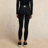 Person wears navy blue leggings with HCE logo on a neutral background