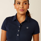 Woman wearing a navy polo shirt with a logo on a beige background