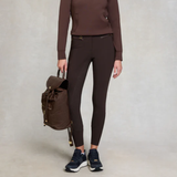 Person wearing brown outfit with backpack on plain background