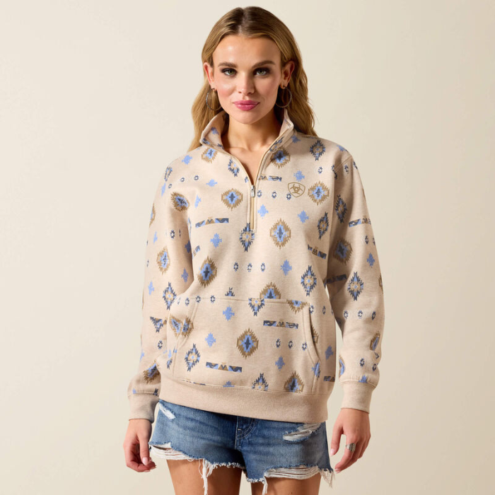 Woman wears a light beige sweatshirt with western pattern on a plain background