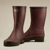 Pair of maroon rubber boots with a visible brand logo on a beige background