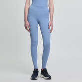 Person wearing light blue leggings and black trainers on a plain background