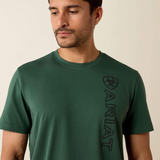 Man wearing a green t-shirt with Ariat logo on a beige background