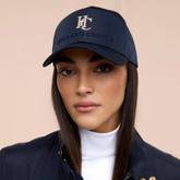 Woman wearing a navy blue cap with 'Holland Cooper' logo on a beige background