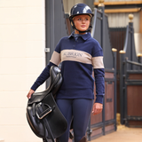 Person in equestrian attire holding a saddle, with 'Aubrion Equestrian' branding.