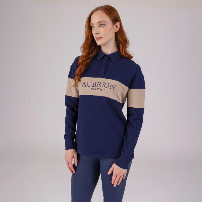 Woman wearing a navy and beige polo shirt with 'Aubrion Equestrian' logo on a plain background