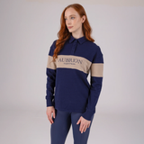 Woman wearing a navy and beige polo shirt with 'Aubrion Equestrian' logo on a plain background