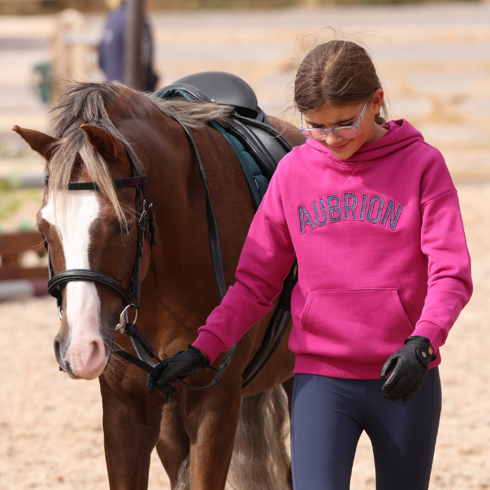 Young person with horse wearing pink hoodie on faded background