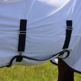 White horse rug with navy blue straps and grass in the background