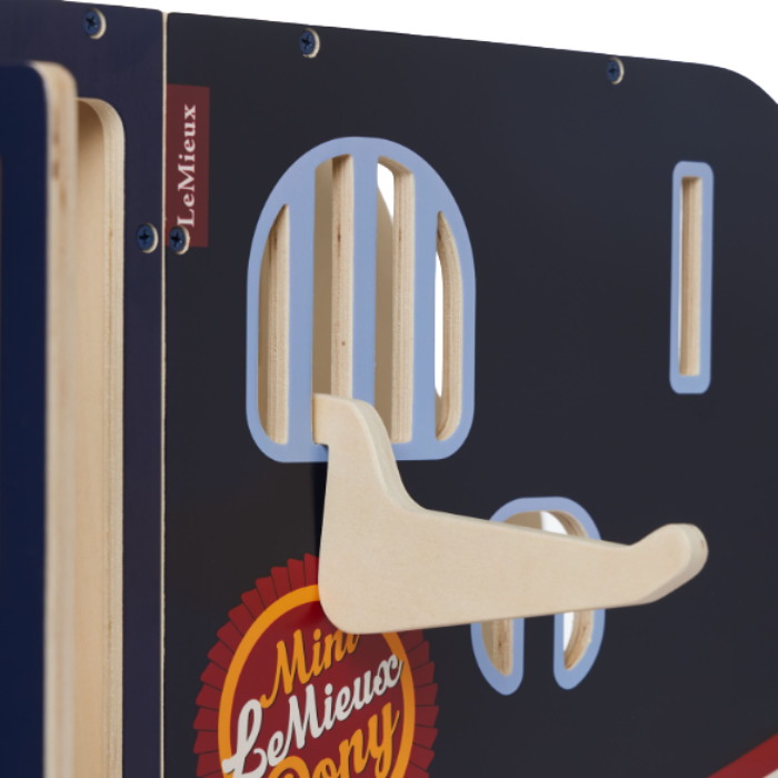 LeMieux AW26 Toy Pony Lorry Wooden Varient Brown. Close-up of a wooden children's toy lorry with cutout shapes, a light wood hook, and visible LeMieux branding on a dark navy panel.