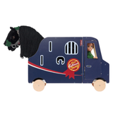 LeMieux AW26 Toy Pony Lorry Wooden Varient Brown. A wooden toy carriage shaped like a horse lorry, shown on a plain white background. The lorry is dark blue with white, red, and yellow graphics, featuring a black knitted horse head with a green bridle and a doll sitting in the driver's seat.