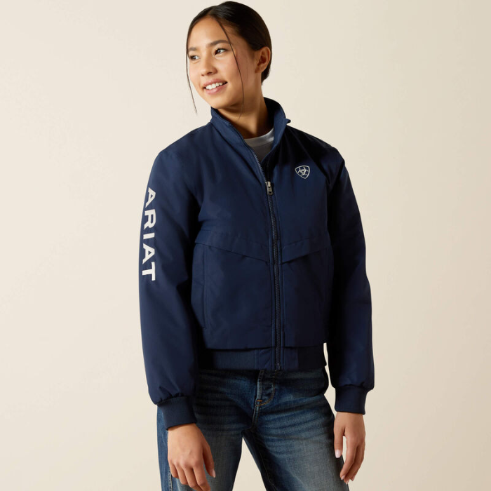 Person wearing a navy blue jacket with 'Ariat' branding on a beige background