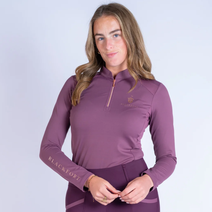 Blackfort Cool Mesh Baselayer AW26-Longsleeve Variant Fig. Woman wearing a fig coloured long sleeve base layer with rose gold detailing against a white background. 