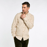 Dubarry Men's Corrib Shirt Variant Ochre. A man wearing a beige and brown checkered long-sleeve button-down shirt and dark green trousers, posing against a light gray studio background.