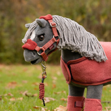 LeMieux AW26 Toy Pony Vogue Headcollar & Leadrope Variant Colour Russet. A plush toy pony wearing a headcollar and leadrope in russet colour with a white faux fur trim on faded garden background.