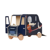 LeMieux AW26 Toy Pony Lorry Wooden Varient Brown. A wooden toy playset shaped like a horse lorry, featuring a dark navy blue printed exterior with a red ribbon graphic and a natural unfinished wood interior and wheels.