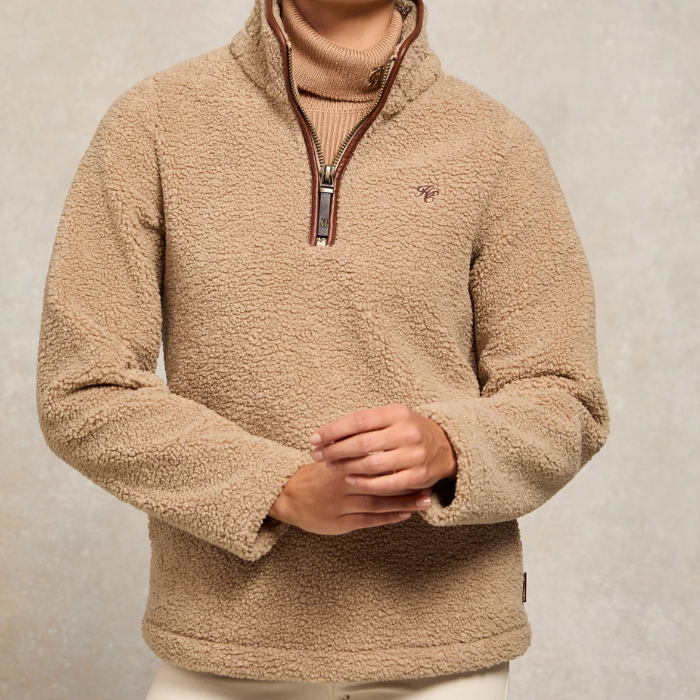 Holland Cooper Ladies Country Fleece Quarter Zip Variant Natural Borg. A woman wearing a beige sherpa fleece quarter-zip pullover sweater with brown trim on the collar and zipper, layered over a tan turtleneck.