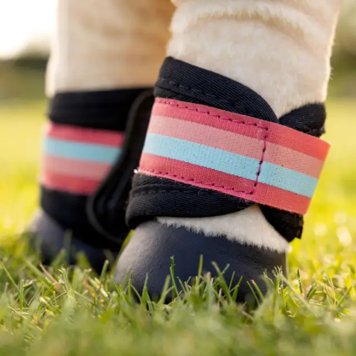 Toy equine boots on plush toy legs on faded back ground