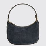 A dark navy blue suede crescent-shaped shoulder bag with gold-tone hardware and a curved top handle, shown against a light gray background.