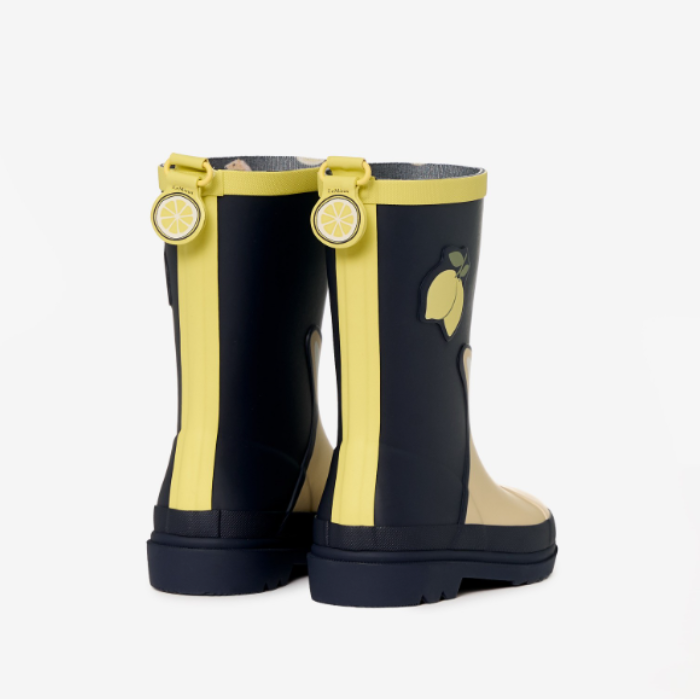 LeMieux AW26 Splash Welly Varient Lemon. A pair of children's rain boots in black and yellow, featuring a lemon graphic on the side and a matching lemon charm on the pull tab.
