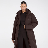 Aztec Diamond Matte Long Puffer AW26 Variant Espresso. A model wearing a long, dark brown hooded puffer jacket over a black athletic outfit, photographed against a clean white studio background.