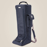 A Navy boot bag with a small side pocket and a red and blue striped handle on a beige background. 